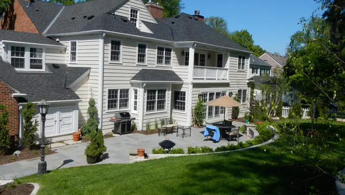 The rear view of a new construction home with a covered up barbecue and patio furniture